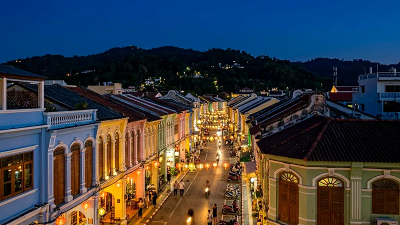 Pastel Sino-Portuguese shophouses with glowing lanterns along Thalang Road at blue hour.